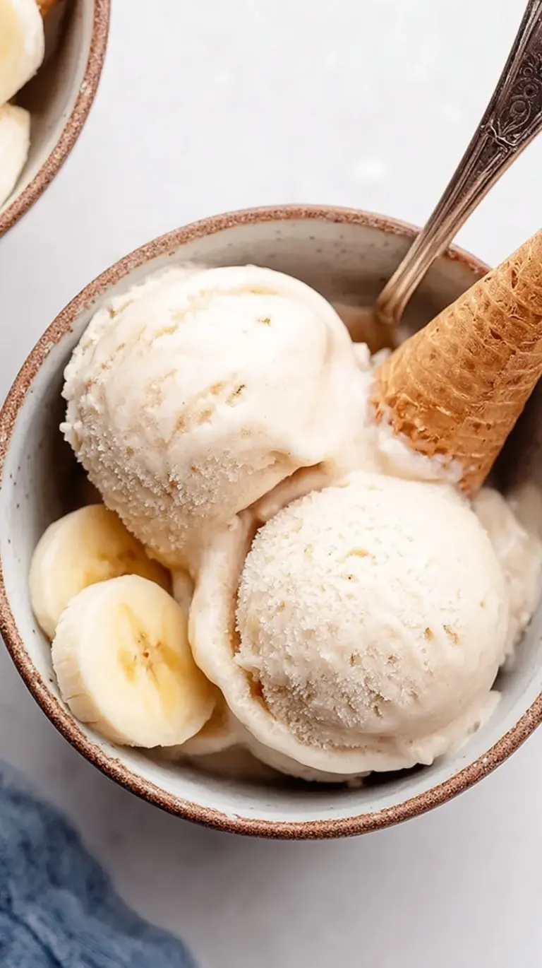 A bowl of smooth, pale yellow banana soft serve ice cream with a spoon.