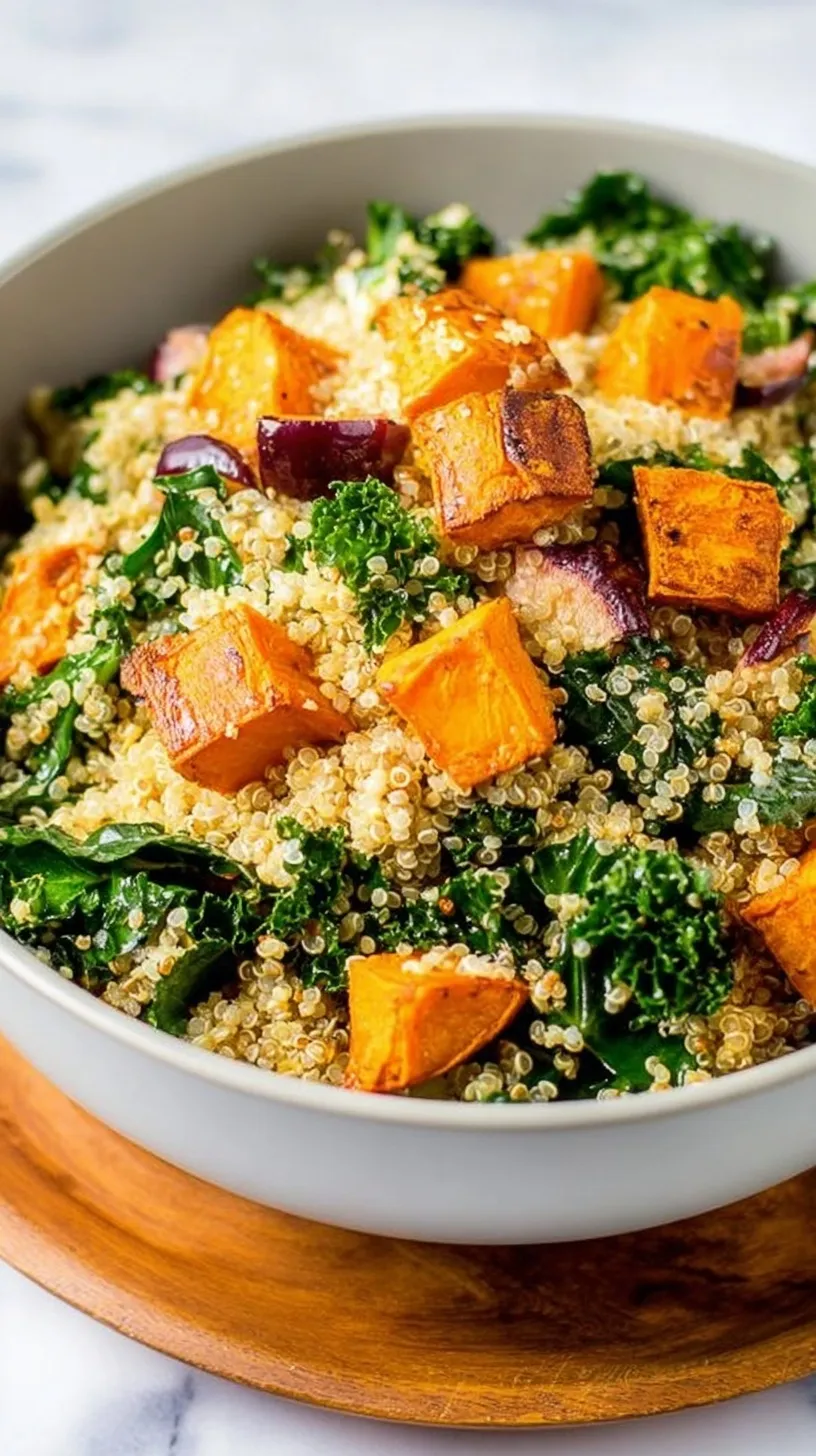 A colorful bowl of quinoa salad with roasted orange sweet potatoes, green kale, and toasted pumpkin seeds.