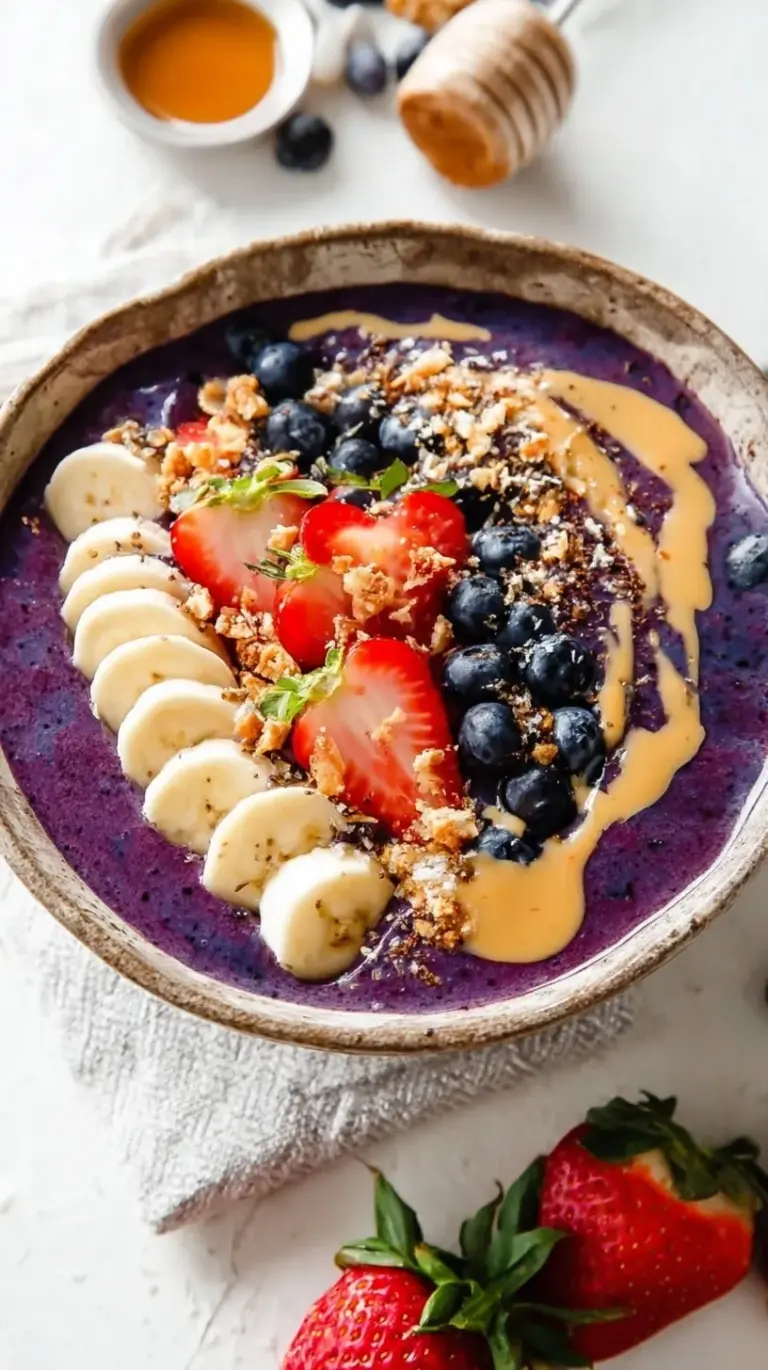 A vibrant purple acai smoothie bowl topped with rows of fresh strawberries, bananas, and granola.