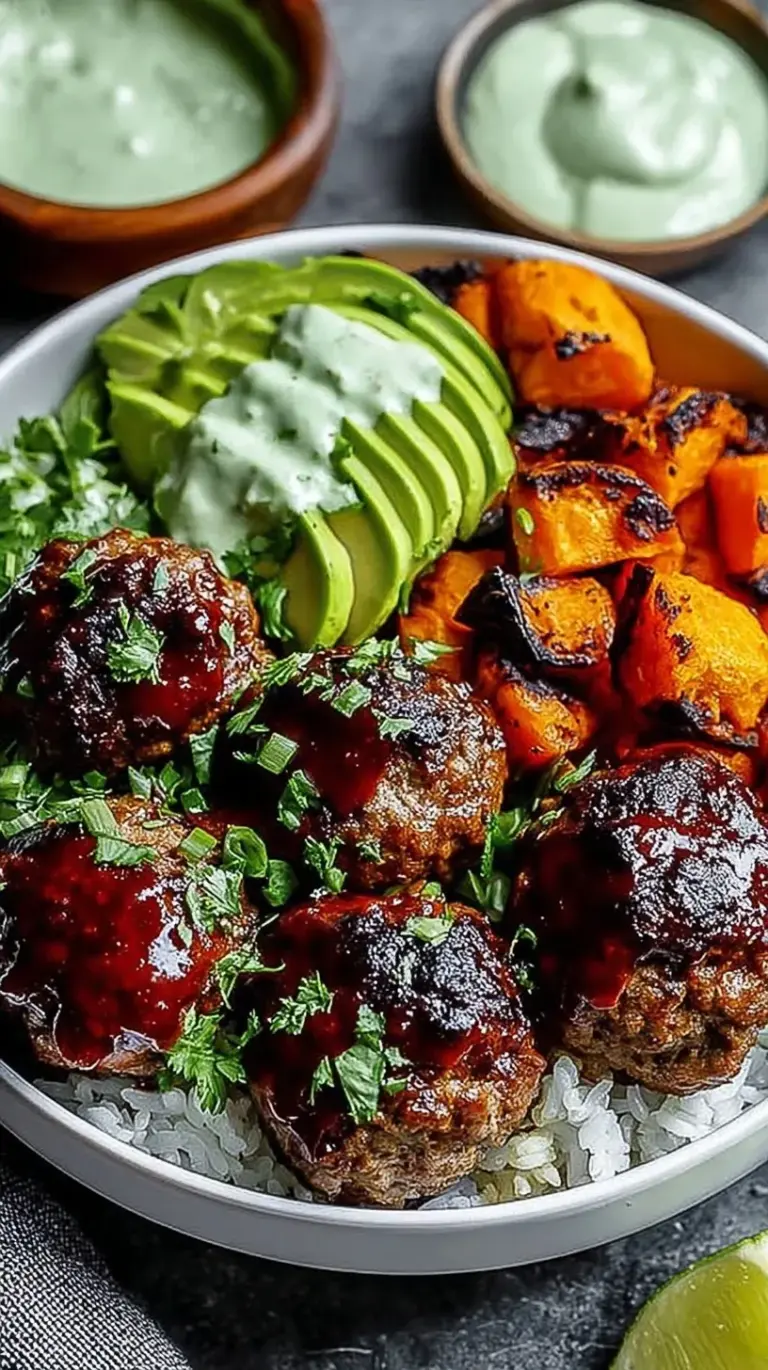 A colorful bowl featuring glazed barbecue meatballs, roasted broccoli, sweet corn, and jasmine rice topped with green avocado sauce.