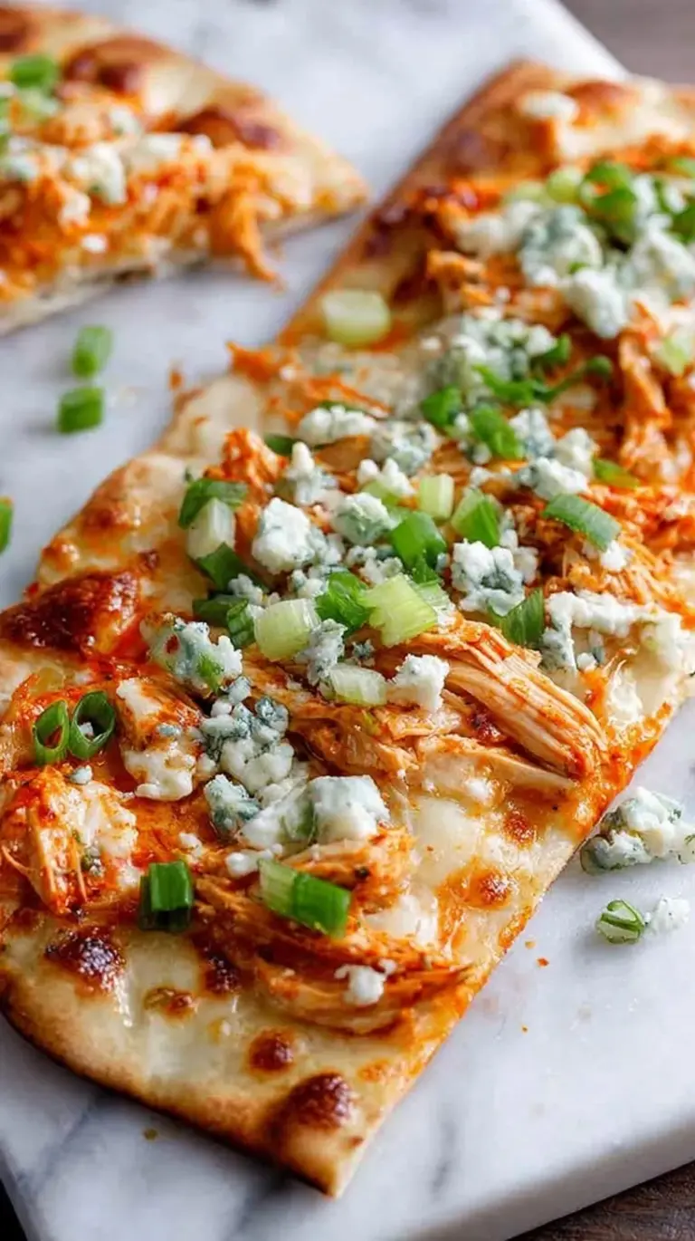 Two crispy buffalo chicken flatbreads topped with melted mozzarella, blue cheese, and ranch drizzle on a baking sheet.