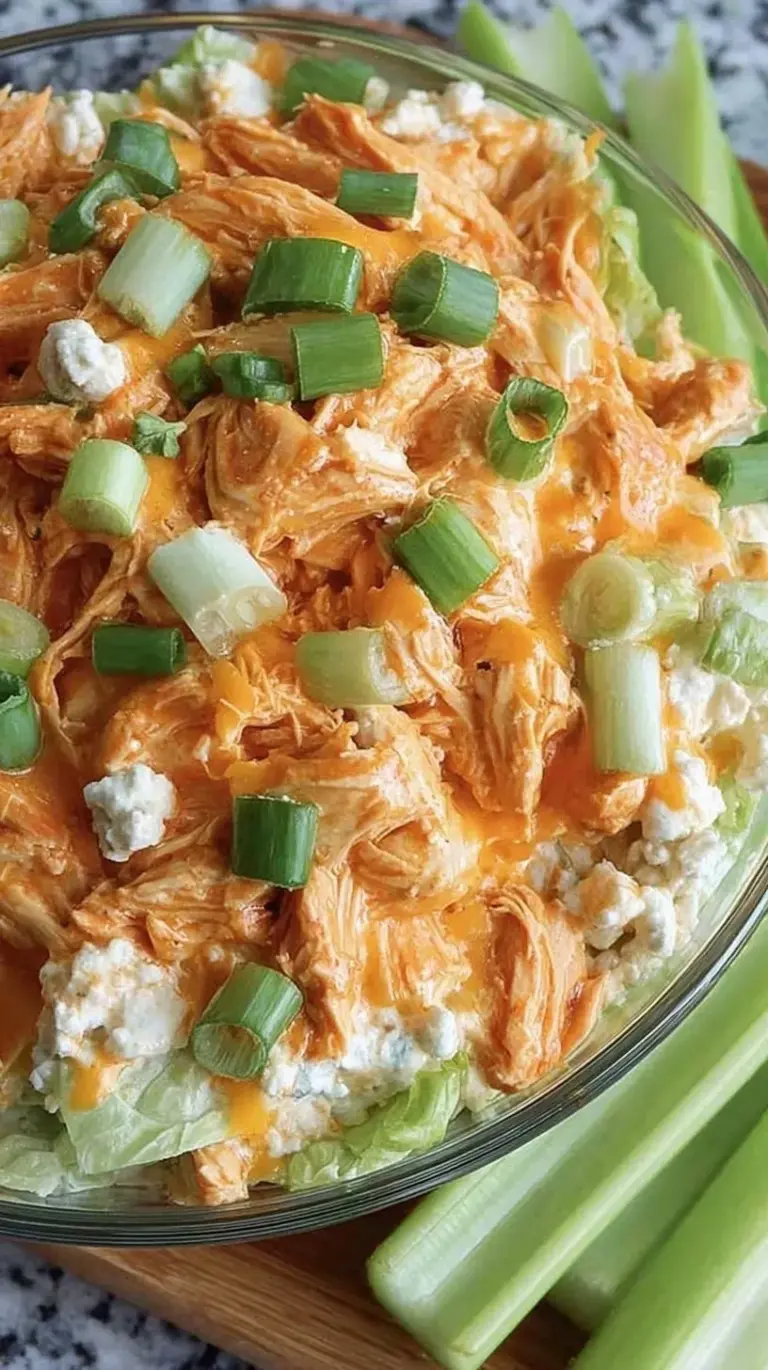 A vibrant bowl of shredded buffalo chicken salad served over fresh mixed greens with blue cheese crumbles