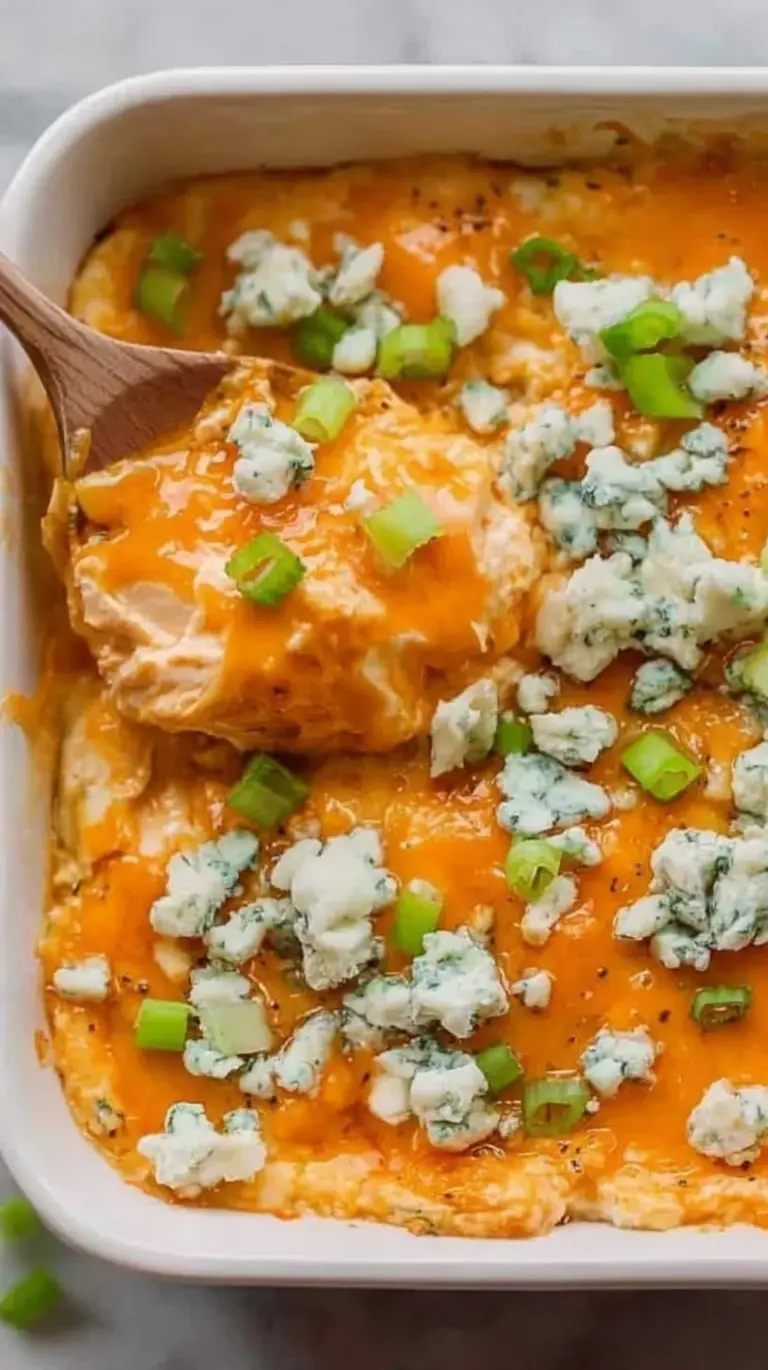 A bubbling dish of creamy buffalo chicken dip topped with melted cheese and green onions.