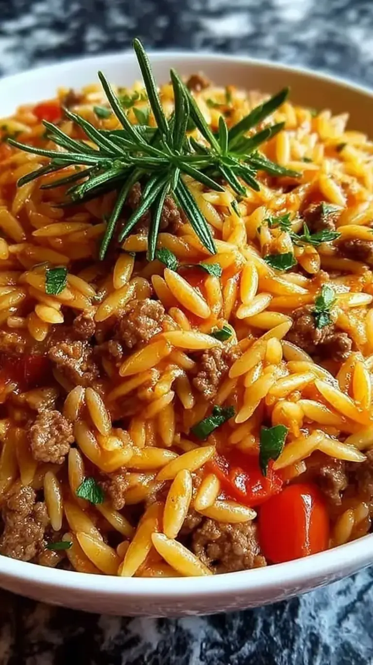 A steaming skillet of ground beef and orzo pasta with melted parmesan and fresh spinach.