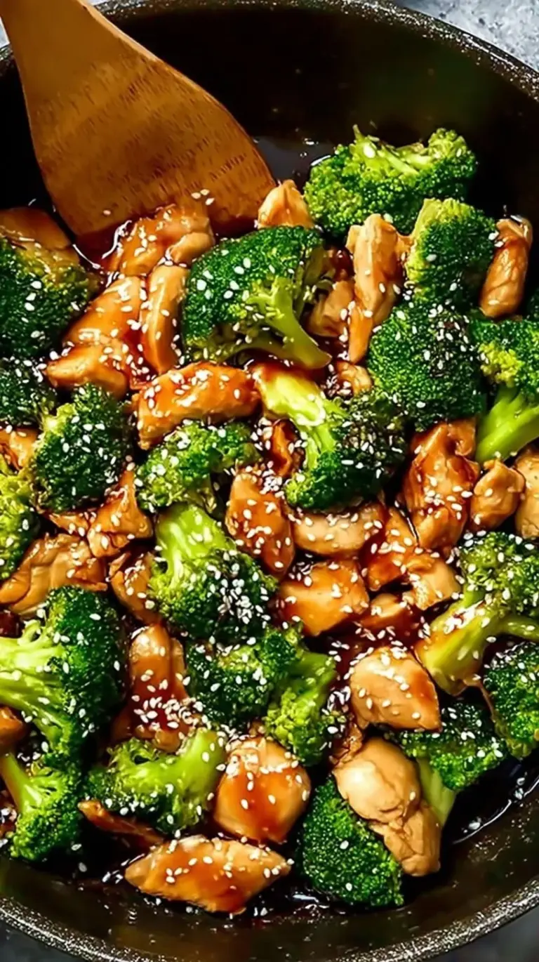 A vibrant skillet filled with golden chicken cubes and bright green broccoli florets in a glossy ginger-soy sauce.