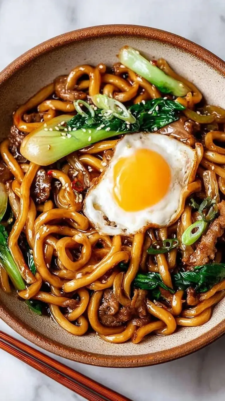 A steaming bowl of High Protein Yaki Udon with thick noodles, golden tofu, and sliced chicken breast.