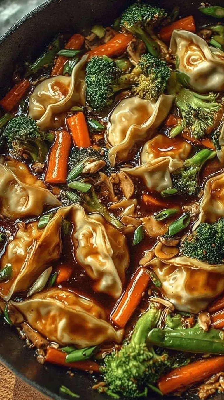 A colorful skillet filled with seared potstickers, shredded cabbage, and red bell peppers garnished with green onions.