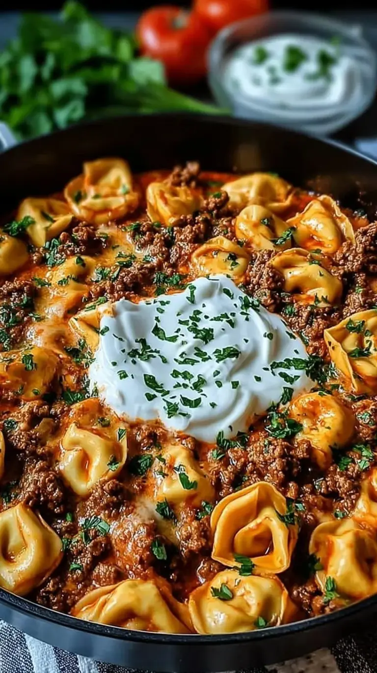 A large skillet filled with cheesy beef enchilada tortellini topped with melted cheese and fresh cilantro.
