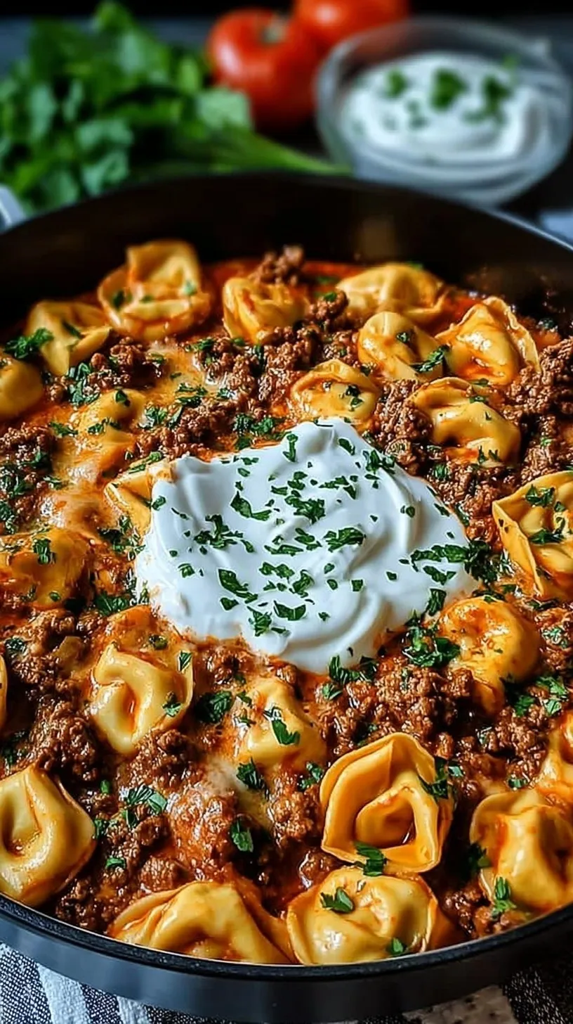 A large skillet filled with cheesy beef enchilada tortellini topped with melted cheese and fresh cilantro.