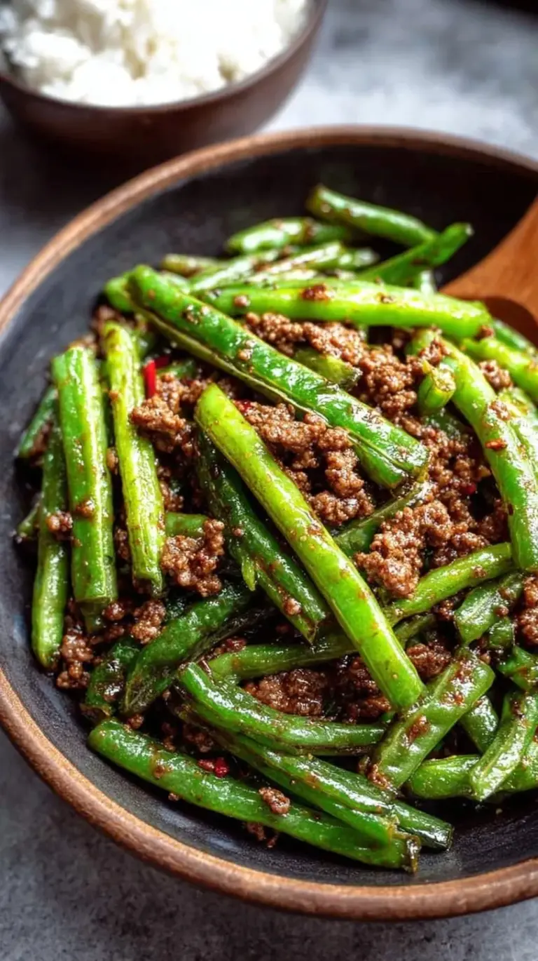 A skillet filled with charred green beans and browned ground beef in a glossy brown sauce.