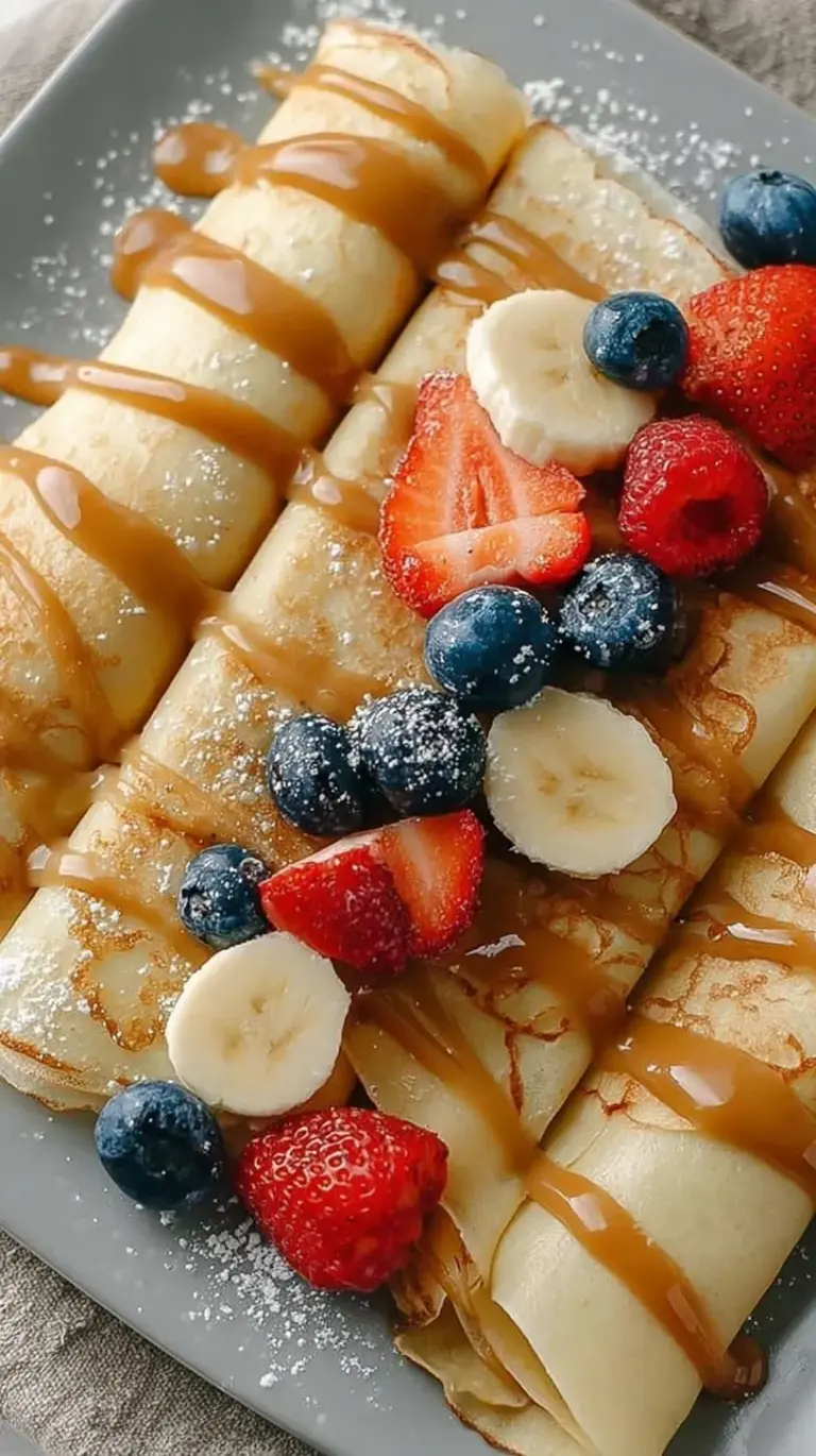 Thin and golden high protein egg white crepes stacked on a white plate with fresh berries