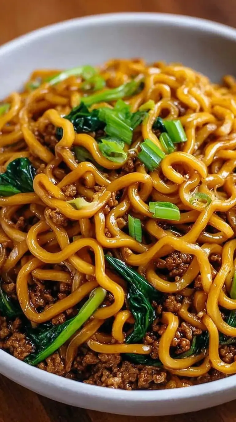 A bowl of high protein Mongolian noodles with seared beef, green broccoli, and bright green onions.